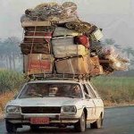 A car with a mountain of luggage on the roof